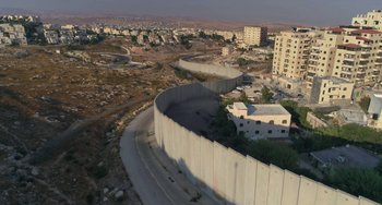 Movie still from “The Two Popes” (2019), directed by Fernando Meirelles – An aerial view of a wall in the middle of a city; Extreme Wide shot, High angle