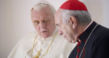 Movie still from “The Two Popes” (2019), directed by Fernando Meirelles – Two men are looking at each other with a serious look on their face; Close Up shot, Over the shoulder angle