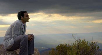 Movie still from “The Two Popes” (2019), directed by Fernando Meirelles – A man sitting on top of a rock on top of a hill; Medium shot, Low angle