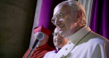 Movie still from “The Two Popes” (2019), directed by Fernando Meirelles – A man with a microphone in front of two other men; Close Up shot, Over the shoulder angle