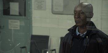 Movie still from “The Unforgivable” (2021), directed by Nora Fingscheidt – A man standing next to a wall in a room; Close Up shot, High angle