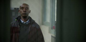 Movie still from “The Unforgivable” (2021), directed by Nora Fingscheidt – A man standing in front of a window in front of a building; Medium shot, Low angle