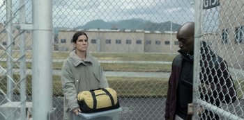 Movie still from “The Unforgivable” (2021), directed by Nora Fingscheidt – A man standing next to another man holding a bag; Medium shot, High angle