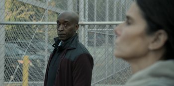 Movie still from “The Unforgivable” (2021), directed by Nora Fingscheidt – A man and a woman standing in front of a chain link fence; Close Up shot, Over the shoulder angle