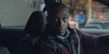 Movie still from “The Unforgivable” (2021), directed by Nora Fingscheidt – A man sitting in the back seat of a car; Close Up shot, Over the shoulder angle