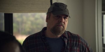 Movie still from “The Unforgivable” (2021), directed by Nora Fingscheidt – A man with a beard wearing a hat and a plaid shirt; Close Up shot, Over the shoulder angle