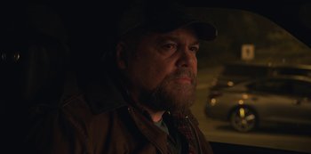 Movie still from “The Unforgivable” (2021), directed by Nora Fingscheidt – A man with a beard wearing a hat and a jacket; Close Up shot, Over the shoulder angle