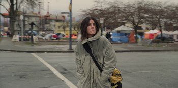 Movie still from “The Unforgivable” (2021), directed by Nora Fingscheidt – A woman is standing on the side of the street; Medium shot, Low angle