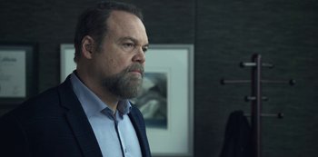 Movie still from “The Unforgivable” (2021), directed by Nora Fingscheidt – A man with a long beard and a suit and tie; Close Up shot, Over the shoulder angle