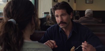 Movie still from “The Unforgivable” (2021), directed by Nora Fingscheidt – A man and a woman sitting at a table talking to each other; Close Up shot, Over the shoulder angle