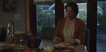 Movie still from “The Unforgivable” (2021), directed by Nora Fingscheidt – A woman sitting at a table writing on a piece of paper; Medium shot, Over the shoulder angle