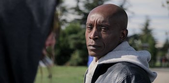 Movie still from “The Unforgivable” (2021), directed by Nora Fingscheidt – An older man is standing in the grass; Close Up shot, Over the shoulder angle