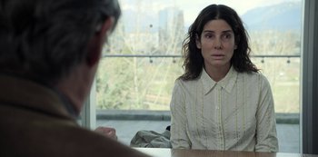 Movie still from “The Unforgivable” (2021), directed by Nora Fingscheidt – A woman sitting in front of a man in front of a window; Close Up shot, Over the shoulder angle
