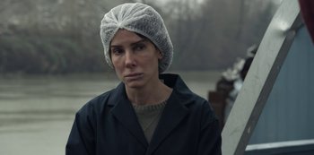 Movie still from “The Unforgivable” (2021), directed by Nora Fingscheidt – A woman wearing a head covering while standing in front of a body of water; Close Up shot, Over the shoulder angle