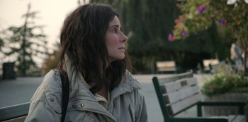 Movie still from “The Unforgivable” (2021), directed by Nora Fingscheidt – A woman sitting on top of a wooden park bench; Close Up shot, Over the shoulder angle