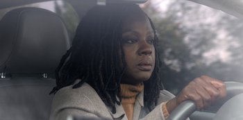 Movie still from “The Unforgivable” (2021), directed by Nora Fingscheidt – A woman with dreads sitting in a car looking out the window; Close Up shot, Over the shoulder angle