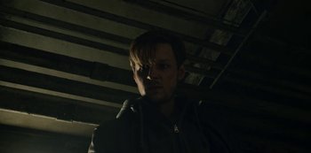 Movie still from “The Unforgivable” (2021), directed by Nora Fingscheidt – A man in a dark room with his head turned to the side; Close Up shot, Low angle