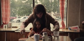 Movie still from “The Unforgivable” (2021), directed by Nora Fingscheidt – A woman and a girl sitting at a dining table; Medium shot, High angle