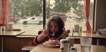Movie still from “The Unforgivable” (2021), directed by Nora Fingscheidt – A young girl eating cake at a restaurant; Medium shot, Over the shoulder angle