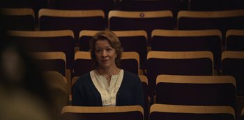 Movie still from “The Unforgivable” (2021), directed by Nora Fingscheidt – A woman sitting alone in an empty auditorium; Medium shot, Over the shoulder angle