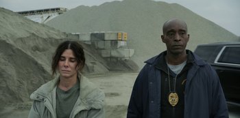 Movie still from “The Unforgivable” (2021), directed by Nora Fingscheidt – A man and a woman standing next to each other in front of a pile of rocks; Medium shot, Low angle