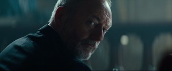 Movie still from “The Vault” (2021), directed by Jaume Balagueró – An older man with a goatee and a beard looking to his left; Close Up shot, Low angle