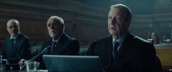 Movie still from “The Vault” (2021), directed by Jaume Balagueró – Two men in business suits sitting in front of a laptop computer; Medium shot, Low angle