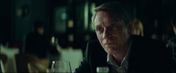Movie still from “The Vault” (2021), directed by Jaume Balagueró – A person sitting at a table with a glass of wine; Close Up shot, Over the shoulder angle