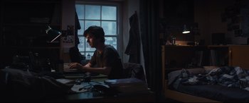 Movie still from “The Vault” (2021), directed by Jaume Balagueró – A man sitting in front of a computer in a dark room; Medium shot, High angle