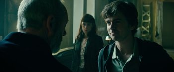 Movie still from “The Vault” (2021), directed by Jaume Balagueró – A group of people standing next to each other in a room; Close Up shot, Over the shoulder angle