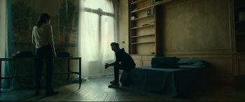 Movie still from “The Vault” (2021), directed by Jaume Balagueró – A man sitting on the floor in front of a window; Wide shot, Low angle