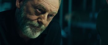 Movie still from “The Vault” (2021), directed by Jaume Balagueró – An older man with a beard looking at the camera; Close Up shot, Low angle
