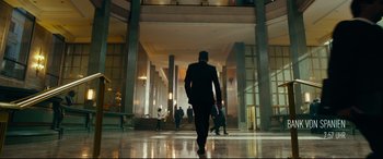 Movie still from “The Vault” (2021), directed by Jaume Balagueró – A man in a suit walks through a lobby; Wide shot, Low angle
