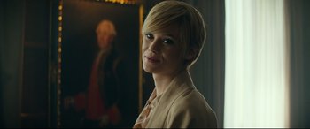 Movie still from “The Vault” (2021), directed by Jaume Balagueró – A woman with short blonde hair wearing a white jacket; Close Up shot, Over the shoulder angle