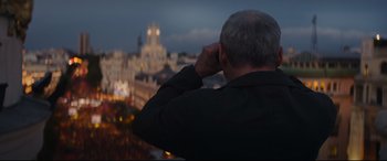 Movie still from “The Vault” (2021), directed by Jaume Balagueró – A man looking out over a city at night; Medium shot, Low angle