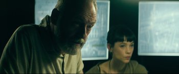Movie still from “The Vault” (2021), directed by Jaume Balagueró – An older man and a young woman sitting in front of a computer; Close Up shot, Low angle