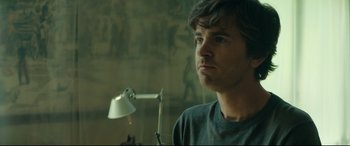 Movie still from “The Vault” (2021), directed by Jaume Balagueró – A man standing in front of a wall with a lamp; Close Up shot, Over the shoulder angle