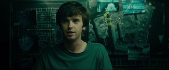 Movie still from “The Vault” (2021), directed by Jaume Balagueró – A young man in a green shirt is in front of a wall; Close Up shot, Over the shoulder angle