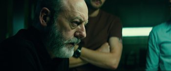 Movie still from “The Vault” (2021), directed by Jaume Balagueró – An older man with a beard and mustache looking at a younger man; Close Up shot, Over the shoulder angle
