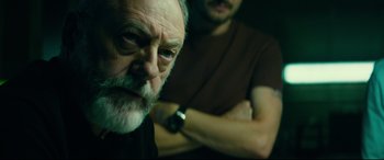 Movie still from “The Vault” (2021), directed by Jaume Balagueró – A man with a beard and a watch in front of another man with a beard; Close Up shot, Over the shoulder angle