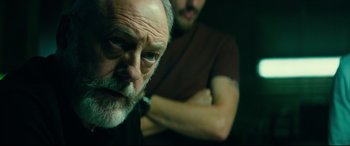 Movie still from “The Vault” (2021), directed by Jaume Balagueró – An older man and a younger man in a dark room; Close Up shot, Over the shoulder angle