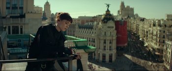 Movie still from “The Vault” (2021), directed by Jaume Balagueró – A woman standing on a balcony looking out over a city; Medium shot, Low angle