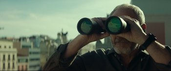 Movie still from “The Vault” (2021), directed by Jaume Balagueró – A man looking through a pair of binoculars; Close Up shot, Low angle