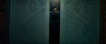 Movie still from “The Vault” (2021), directed by Jaume Balagueró – A man standing in an elevator looking out the door; Medium shot, Over the shoulder angle