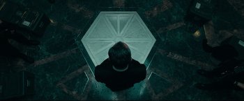 Movie still from “The Vault” (2021), directed by Jaume Balagueró – A man sitting on the floor looking up at the sky; Medium shot, Overhead angle