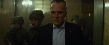 Movie still from “The Vault” (2021), directed by Jaume Balagueró – A person wearing a suit and tie; Close Up shot, Low angle