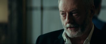 Movie still from “The Vault” (2021), directed by Jaume Balagueró – An older man in a black suit looking at the camera; Close Up shot, Low angle