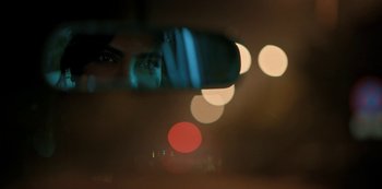 Movie still from “The White Tiger” (2021), directed by Ramin Bahrani – A blurry image of a man's face in a car's mirror; Extreme Close Up shot, Over the shoulder angle