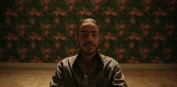 Movie still from “The White Tiger” (2021), directed by Ramin Bahrani – A man sitting in front of a wall with his eyes closed; Close Up shot, Overhead angle