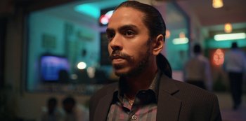 Movie still from “The White Tiger” (2021), directed by Ramin Bahrani – A person wearing a suit and tie; Close Up shot, Low angle